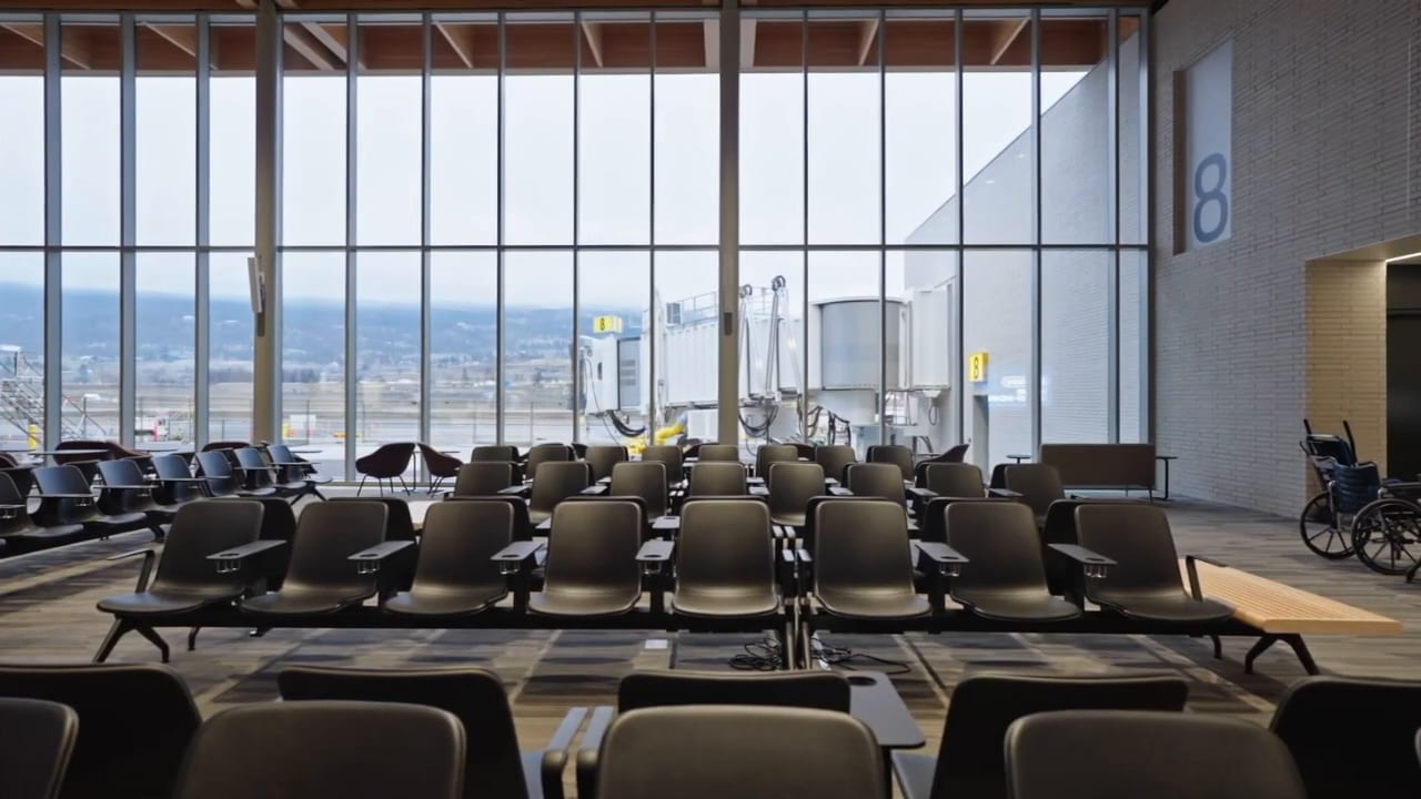 A tall glass curtain wall running the length of a public hall, with rows of seating in front of it.